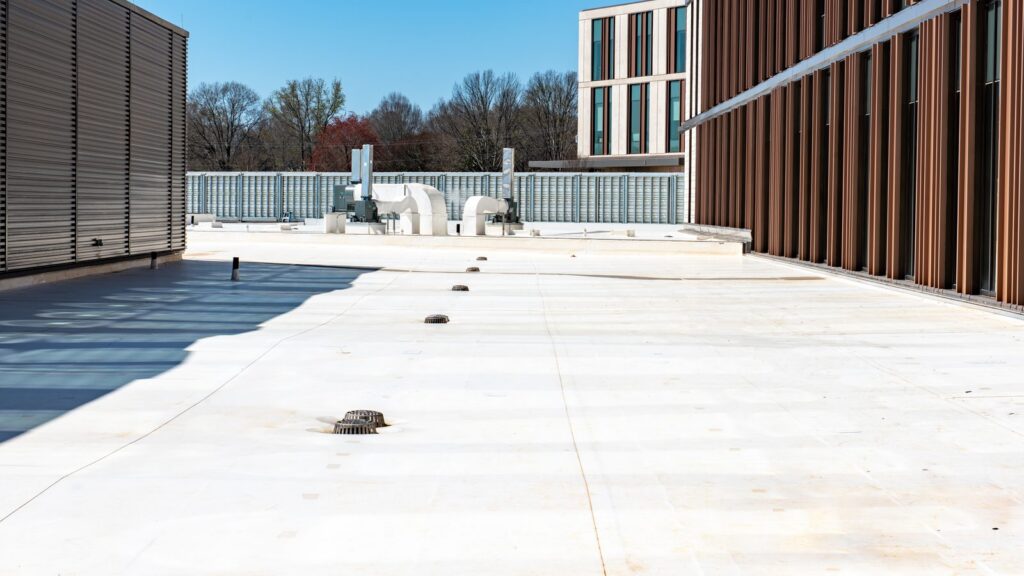 White membrane commercial roof with roof drains, walkway pads and rooftop equipment