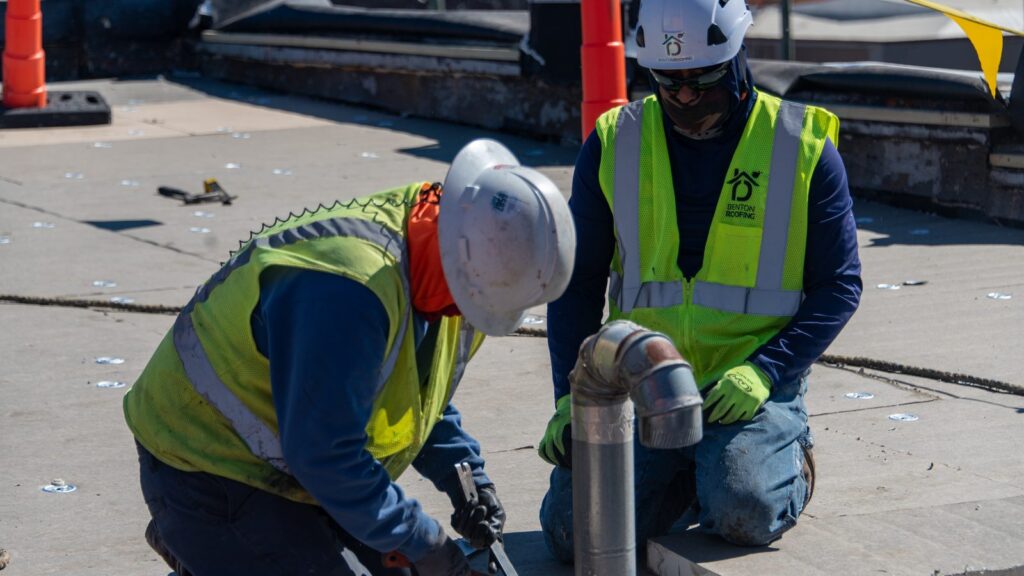 Benton Roofing crew flashing a pipe penetration on a commercial flat roof