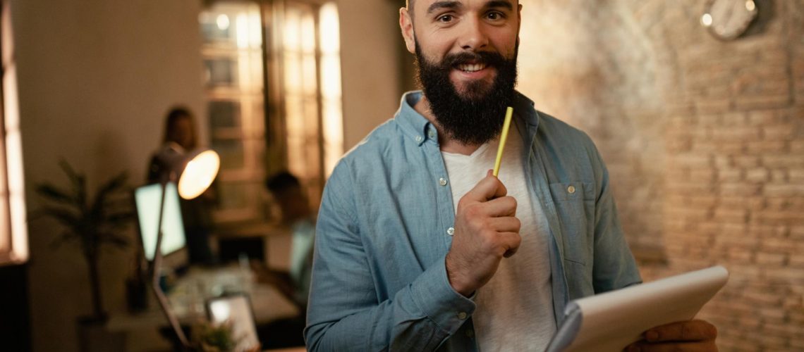 portrait-happy-businessman-analyzing-reports-while-working-late-office